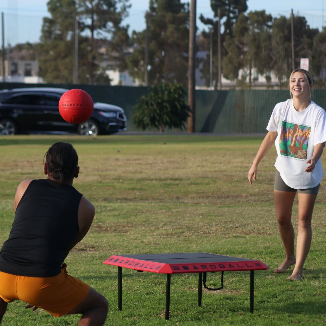 guy bumping volleyball in a game of boardball at the park in california